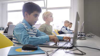 Junge beim E-Learning mit Laptop am Schreibtisch in der Schule