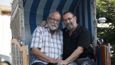 Das schwule Ehepaar, Bernd Göttling und Dieter Schmitz sitzt arm in arm in einem Strandkorb