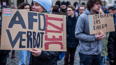 Eine Teilnehmerin einer Demonstration gegen Rechtsextremismus unter dem Motto «Nie wieder ist jetzt - alle zusammen gegen den Faschismus» trägt auf dem Neuen Markt vor dem Rathaus ein Schild mit der Aufschrift «AFD-Verbot jetzt»
