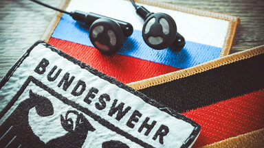 Bundeswehr-Aufnäher und Kopfhörer auf Russland-Fahne, Symbolfoto Taurus-Abhöraffäre 