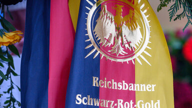 "Reichsbanner Schwarz-Rot-Gold" steht auf einer Schleife an einem Kranz. 