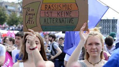 Zwei Frauen mit einem Schild "Rassissmus ist keine ALternative" stehen bei einer Demonstration für Europa