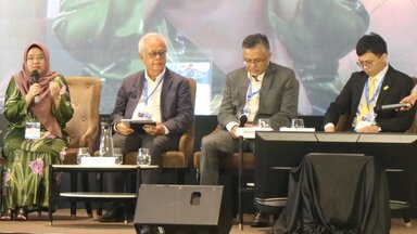 A photo of one of the sessions in Malaysia Outlook Conference 2024. Four people are sitting on individual chairs in front of a big screen on the stage. They are: Aira Azhari (Moderator), Ibrahim Suffian (Panelist), Ooi Kok Hin (Panelist), and Datuk Dr. Johan Arriffin Samad (Panelist).