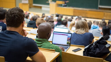 Studierende sitzen mit Laptops in einer Vorlesung.