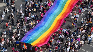 Menschen ziehen auf der 45. Berlin Pride-Parade zum Christopher Street Day (CSD) mit einer überdimensionalen Regenbogenfahne durch die Stadt. 