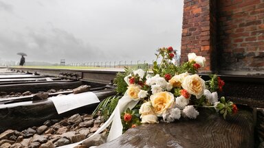 KZ Auschwitz Besucher haben an dem Einfahrttor zum Konzentrationslager Auschwitz-Birkenau Blumen auf die Schienen auf denen massenweise Gefangene angekommen sind abgelegt.