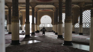 Un homme porte un tapis dans  la Grande Mosquée de Touba, au Sénégal.