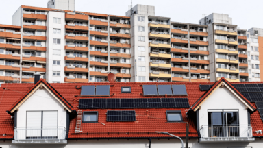 Hohe Wohnhäuser sind am 21.11.2024 in München (Bayern) hinter dem Dach eines modernen Mehrfamilienhauses zu sehen. 