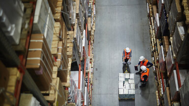 Blick von oben auf Arbeiter, die in einer Halle stehen. 