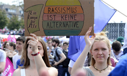 Zwei Frauen mit einem Schild "Rassissmus ist keine ALternative" stehen bei einer Demonstration für Europa