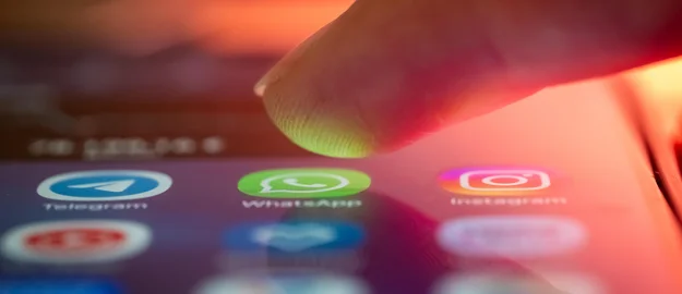 Finger schwebt über dem WhatsApp-Icon auf einem Smartphone.